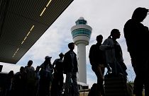Путешественники стоят в очереди у здания терминала для регистрации и посадки на рейсы в амстердамском аэропорту Схипхол.