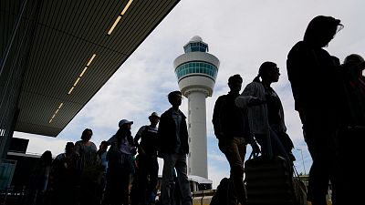 Путешественники стоят в очереди у здания терминала для регистрации и посадки на рейсы в амстердамском аэропорту Схипхол.