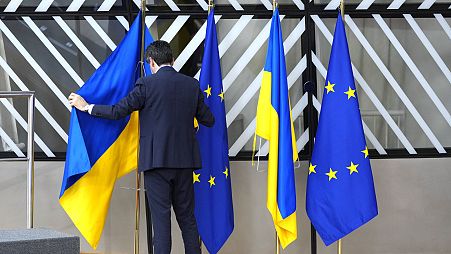 A member of protocol arranges the Ukrainian and EU flags during an EU summit at the European Council building in Brussels on Thursday, Feb. 9, 2023. 