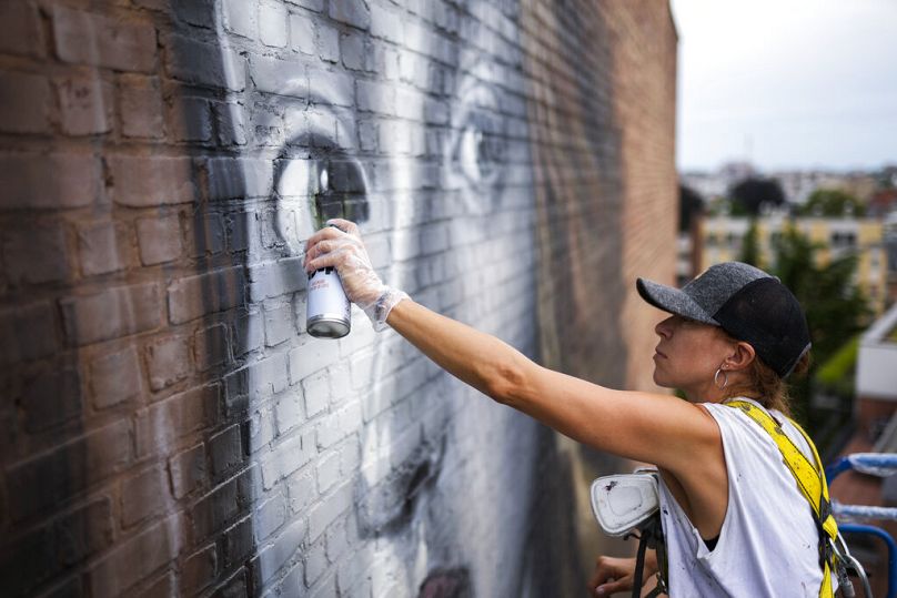 Spanish street artist Lula Goce works in a giant mural in Brussels, July 2021