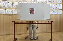 A woman prepares her ballots for the European Parliament elections at a polling station in Prague, Czech Republic, Friday, June 7, 2024.