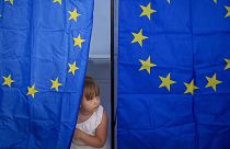 A child peers from a voting cabin during European and local elections in Baleni, 9 June 2024