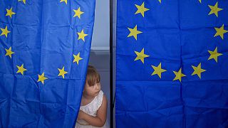 A child peers from a voting cabin during European and local elections in Baleni, 9 June 2024