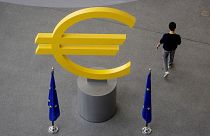 Ένας άνδρας περπατά μπροστά από μια πινακίδα ευρώ στο διάδρομο της Ευρωπαϊκής Κεντρικής Τράπεζας στη Φρανκφούρτη της Γερμανίας,