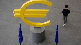 Un hombre pasa junto a un cartel del euro en el vestíbulo del Banco Central Europeo en Fráncfort, Alemania.