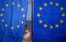 Ребенок на избирательном участке с флагами Евросоюза 
