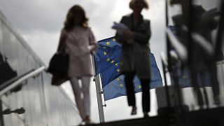 FILE - Two women walk near EU flags outside the European Commission headquarters in Brussels, Monday, May 27, 2019. 