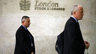 Men walk past a logo outside the London Stock Exchange in the City of London, Tuesday Oct.14, 2008.