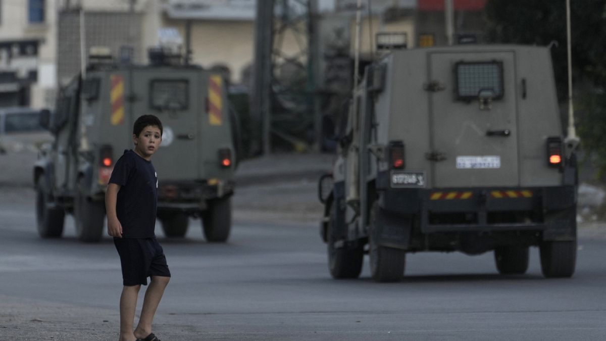 طفل فلسطيني يراقب مرور المركبات المدرعة التابعة للقوات الإسرائيلية في مخيم بلاطة للاجئين في مدينة نابلس بالضفة الغربية