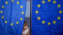 Un niño mira desde una cabina de votación durante las elecciones europeas y locales en Baleni, Rumanía.