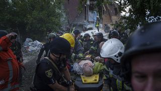 Rescue workers and police officers carry an injured person by a stretcher to an ambulance from a building which was destroyed by a Russian airstrike in Kharkiv, Ukraine.