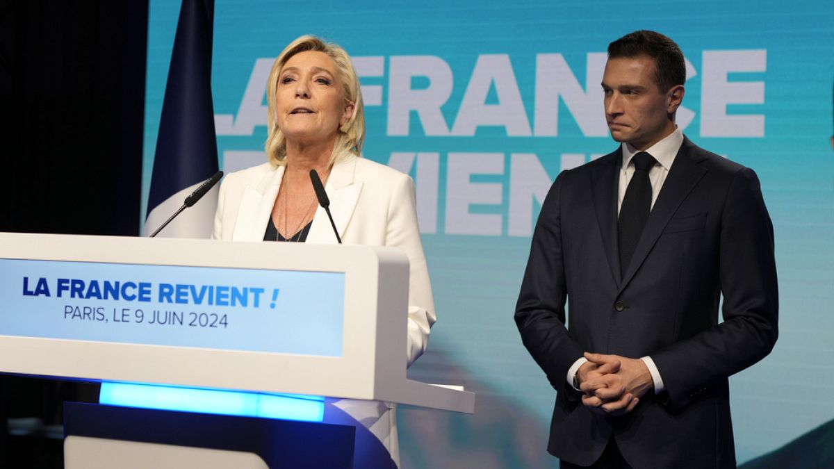 Marine Le Pen francia szélsőjobboldali vezető beszél, miközben Jordan Bardella, a francia szélsőjobboldali Nemzeti Összefogás elnöke hallgatja a párt vasárnap esti választási székházában, 