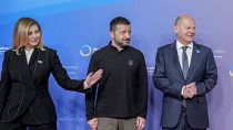 الرئيس الأوكراني فولوديمير زيلينسكي، في الوسط، والمستشار الألماني أولاف شولتس، إلى اليمين، وأولينا زيلينسكا، في بداية مؤتمر إعادة إعمار أوكرانيا في برلين، ألمانيا، الثلاثاء 11