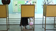 A woman with her child casts her ballot during the European and local Elections in capital Nicosia, Cyprus, Sunday, June 9, 2024. 