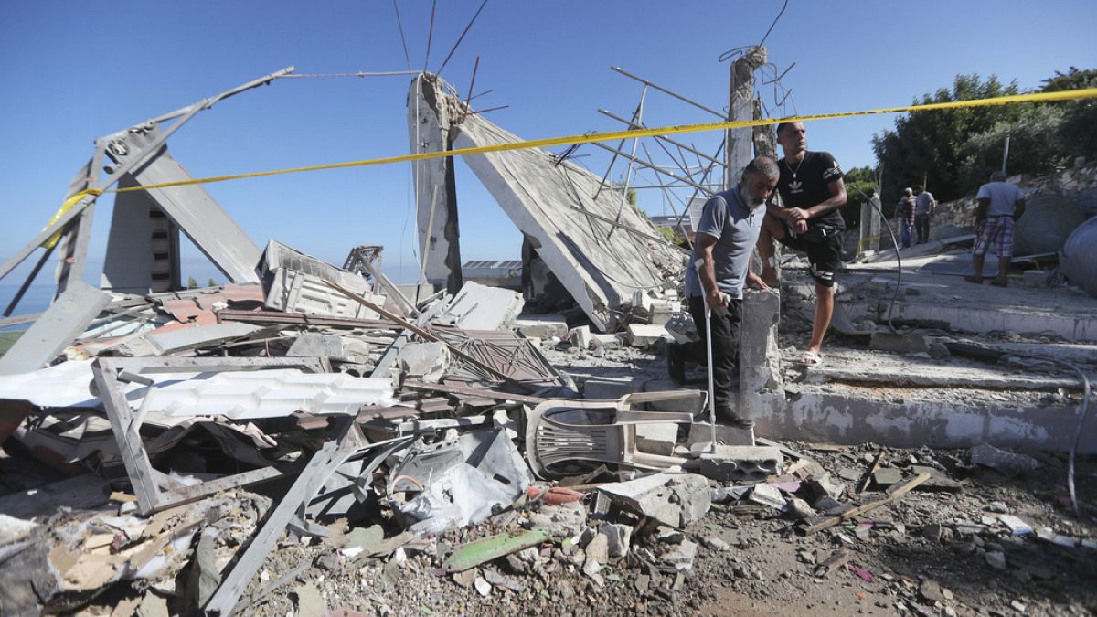 رجال لبنانيون يتفقدون منزلا مدمرا ضربته غارة جوية إسرائيلية ليلة الجمعة