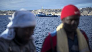 Menekültek. Háttérben a Sea Watch civil szervezet mentőhajója