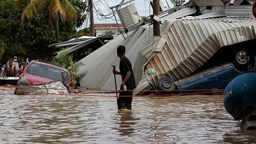 En esta foto de archivo del 6 de noviembre de 2020, un residente que camina por una calle inundada mira hacia atrás a los daños causados por la tormenta del huracán Eta en Planeta, Honduras.