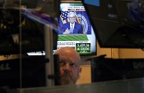 Federal Reserve Chairman Jerome Powell is framed by a trader's screens on the floor of the New York Stock Exchange 