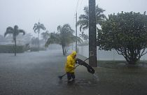 A man works to clear debris from a flooded street as heavy rain falls over parts of South Florida on Wednesday, June 12, 2024, in Hollywood, Fla. 