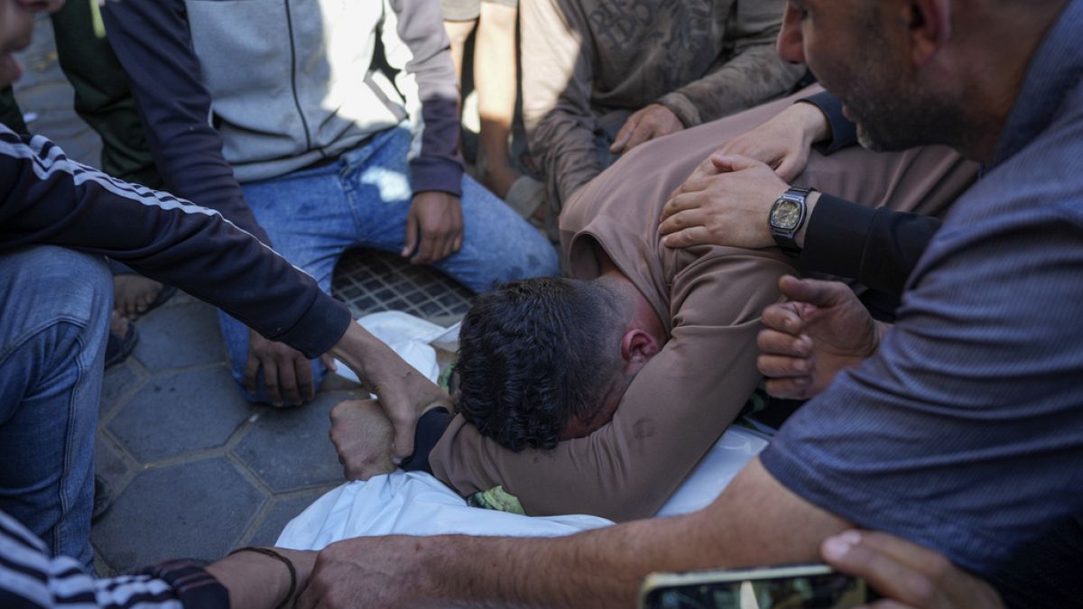 فلسطينيون يبكون خلال تشييع جثمان البالغين والأطفال الذين استشهدوا جراء القصف الإسرائيلي على قطاع غزة