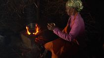Jane Muthoni Njenga making a fire on firewood