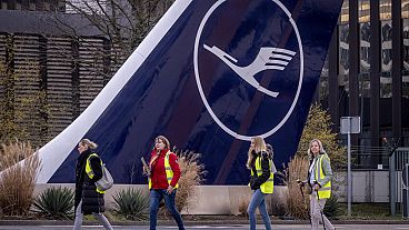 Striking Lufthansa flight attendants walk past a tail of an aircraft in Frankfurt, Germany, Tuesday, March 12, 2024. 