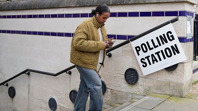 A woman leaves a polling station after voting in London.