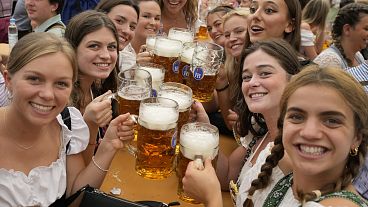 Women with glasses of beer pose for a photo on day one of the 188th 'Oktoberfest' beer festival in Munich, Germany