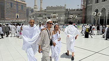 Two blind pilgrims preform Hajj with the help of their guide outside of the Grand Mosque during the annual pilgrimage in Mecca, Saudi Arabia, Thursday, June 13, 2024.