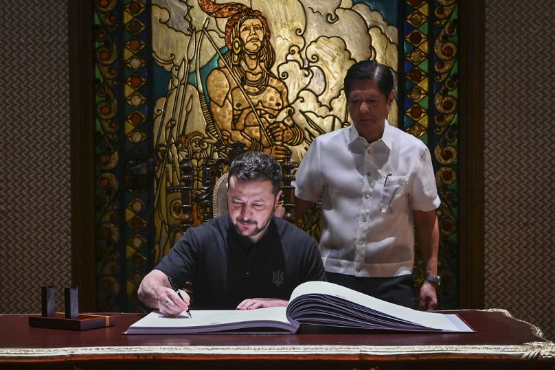 Ukraine's President Volodymyr Zelenskyy, left, signs the guest book beside Philippine President Ferdinand Marcos Jr. at the Malacanang presidential palace in Manila, 2024.