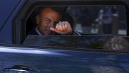 Президент Франции Эмануэль Макрон выглядывает с улыбкой из окна лимузина.