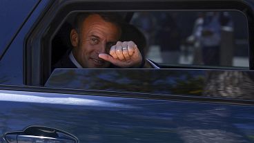 O presidente francês Emmanuel Macron levanta o polegar do seu carro depois de votar nas eleições europeias, domingo, 9 de junho de 2024
