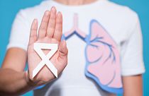 یک زن با نقش ریه‌های کاغذی و روبان سفیدی که نماد آگاهی از سرطان ریه است 