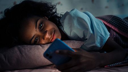 A woman in bed with her phone.
