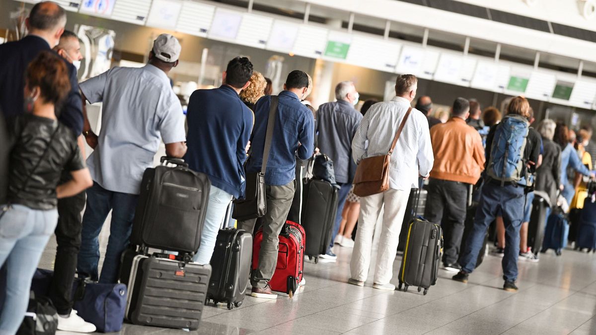 Viajantes aéreos em fila no Terminal 1 do Aeroporto de Frankfurt em frente a um balcão de check-in, Alemanha, 15 de junho de 2020. 