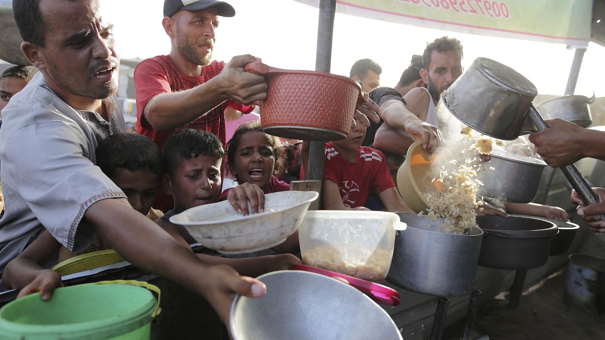Palestinesi ricevano aiuti alimentari a Khan Younis, nella Striscia di Gaza (15 giugno 2024)