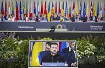 Ukrainian President Volodymyr Zelenskyy is seen on the screen during the plenary session during the Summit on peace in Ukraine, in Obbürgen, Switzerland, Sunday, June 16, 2024