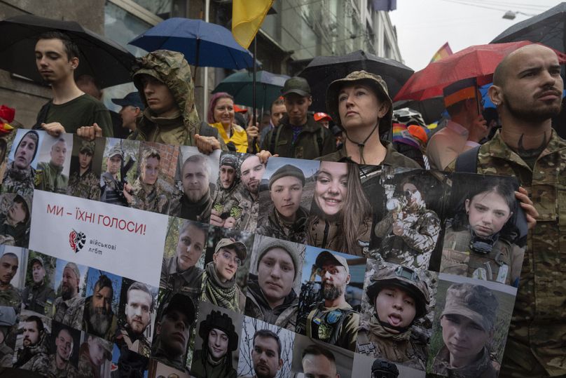 جنود يحملون صورًا لجنود أوكرانيين من مجتمع المثليين، الذين يقاتلون على الخطوط الأمامية