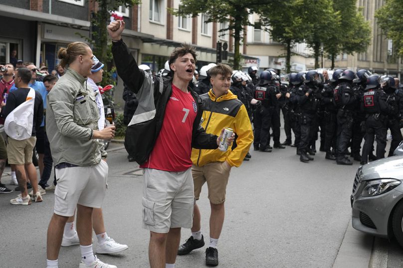 England soccer fans cheer in front of police ahead the Group C match between Serbia and England at the Euro 2024 in Gelsenkirchen, Germany, Sunday, June 16, 2024.