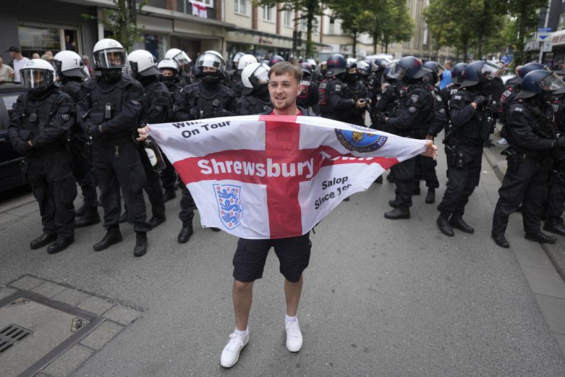 Un supporter anglais applaudit devant la police avant le match du groupe C entre la Serbie et l'Angleterre lors de l'Euro 2024 à Gelsenkirchen, en Allemagne