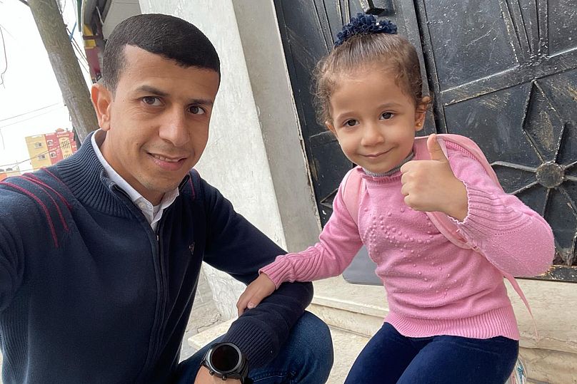 رمزي أبو القمصان مع ابنته نور، خارج منزلهم في مخيم جباليا للاجئين بغزة في 22 أكتوبر 2022.