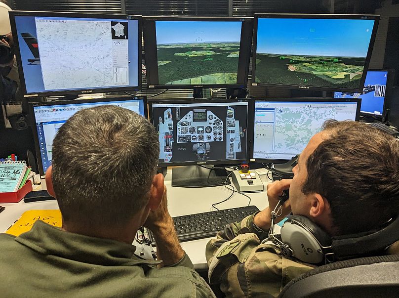 Dois instrutores da Força Aérea Francesa supervisionam uma sessão de treino para um piloto ucraniano num simulador, no sudoeste de França, a 14 de junho de 2024.