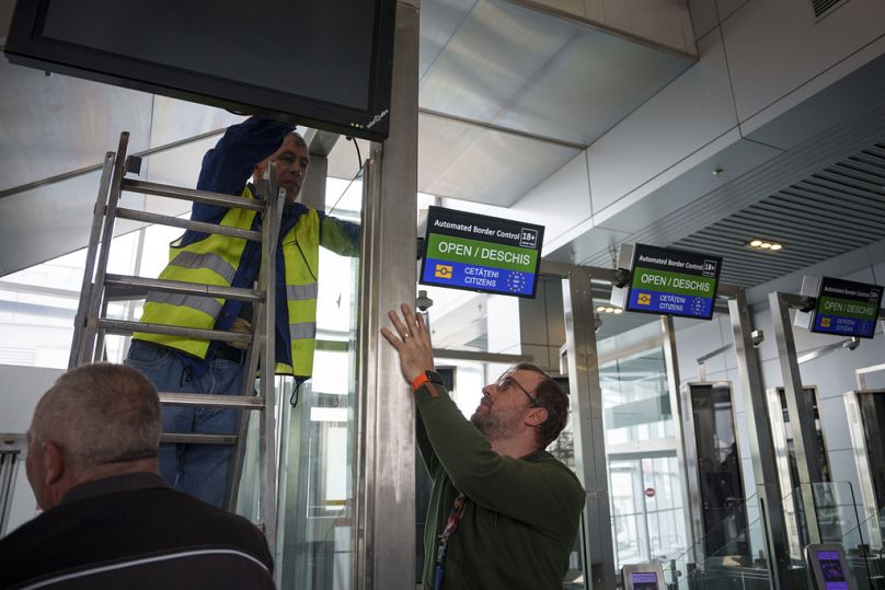 Airport employees install an Information sign next to Non-Schengen automatic border control gates, at the Henri Coanda International Airport near Bucharest, March 2024