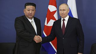 Vladimir Putin e  Kim Jong Un apertam as mãos durante uma reunião a 13 setembro 2023