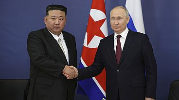 Vladimir Putin e  Kim Jong Un apertam as mãos durante uma reunião a 13 setembro 2023