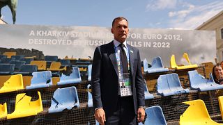 Ukraine Football Association chief Andriy Shevchenko stands in front of the rests of a bombarded Ukrainian football stadium