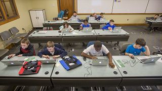 As crianças trabalham com computadores portáteis durante a aula.