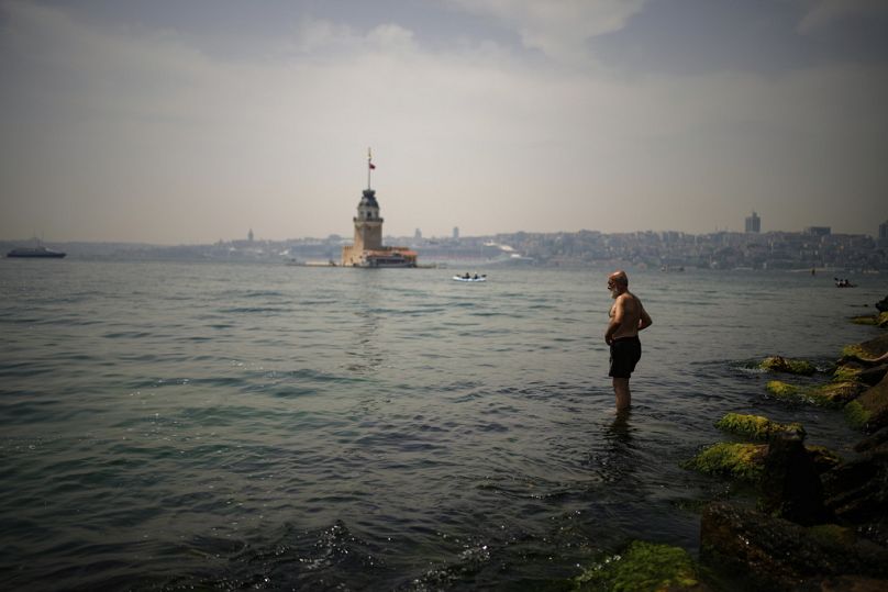 Un hombre se refresca en el Bósforo durante un día caluroso en Estambul, Turquía, jueves 13 de junio de 2024. 