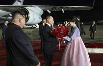 Vlagyimir Putyin üdvözlő csokrot kap a phenjani repülőtéren