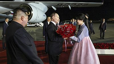 Vlagyimir Putyin üdvözlő csokrot kap a phenjani repülőtéren